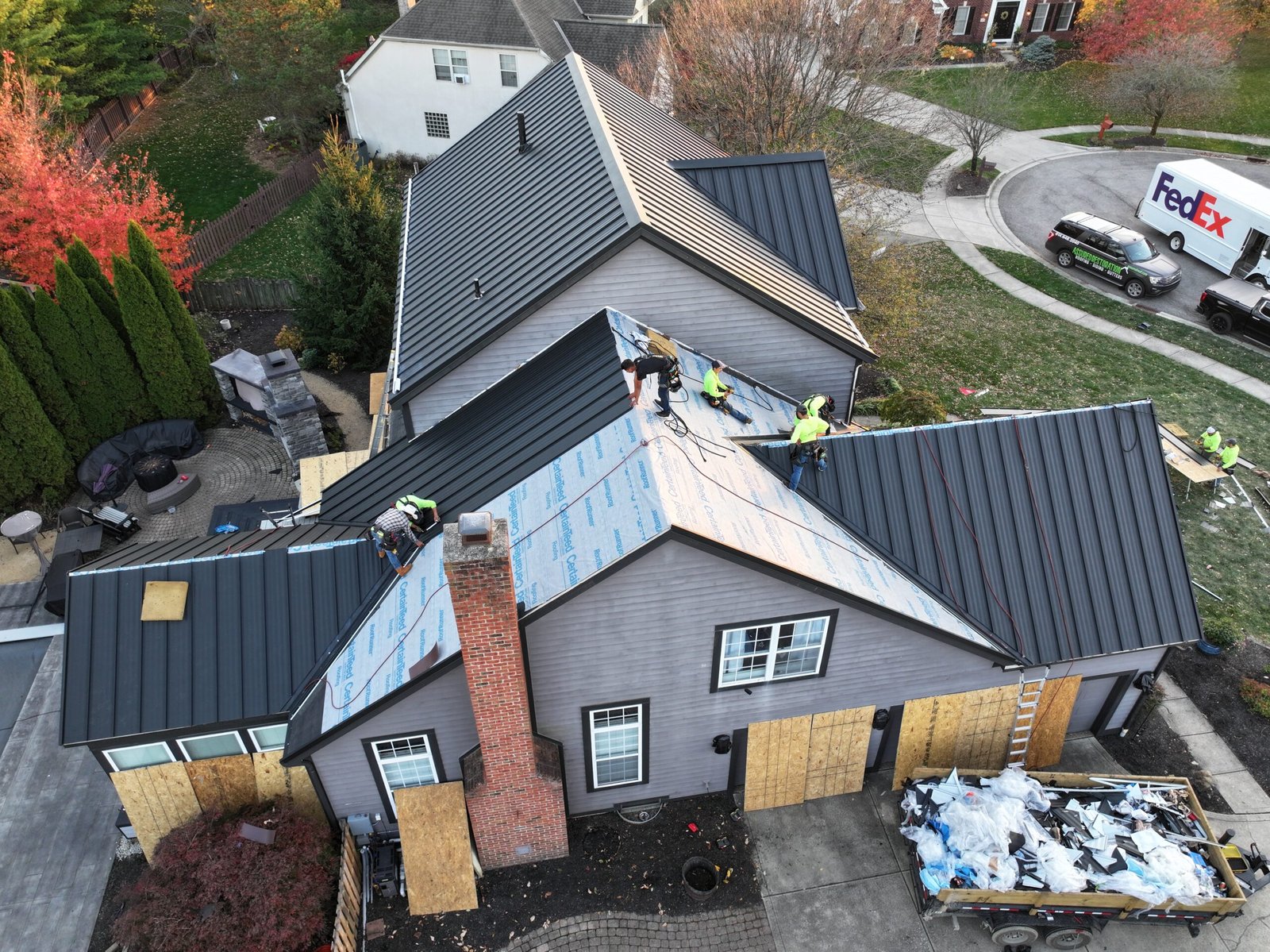 Assured Restoration crew installing black standing seam metal roofing on a complex Central Ohio home