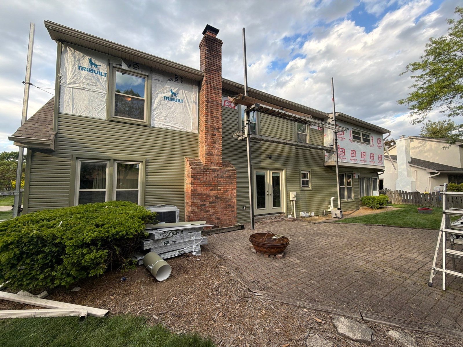 Green siding being installed on the same home