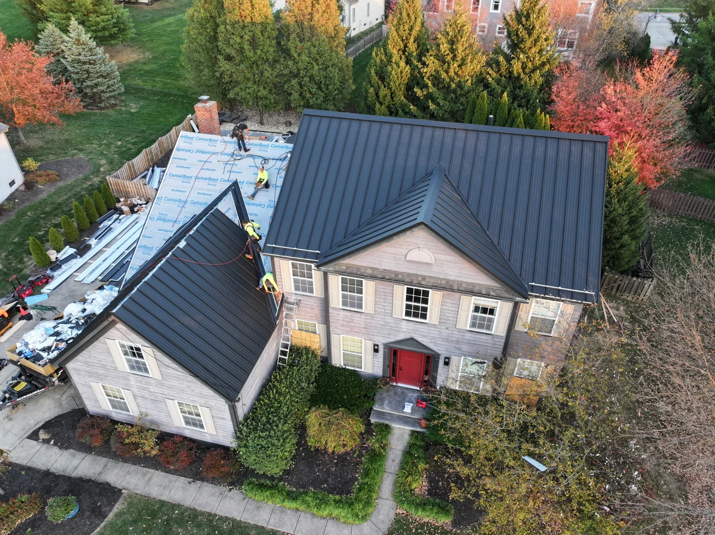 Crew installing a standing seam metal roof, with underlayment still exposed in unfinished sections